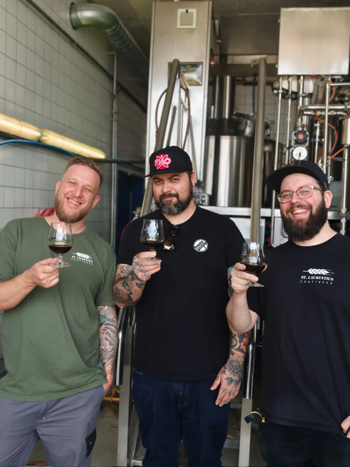 John from St. Laurentius, Thiago from Hoppy People and Sandro holding glasses in the brewhouse