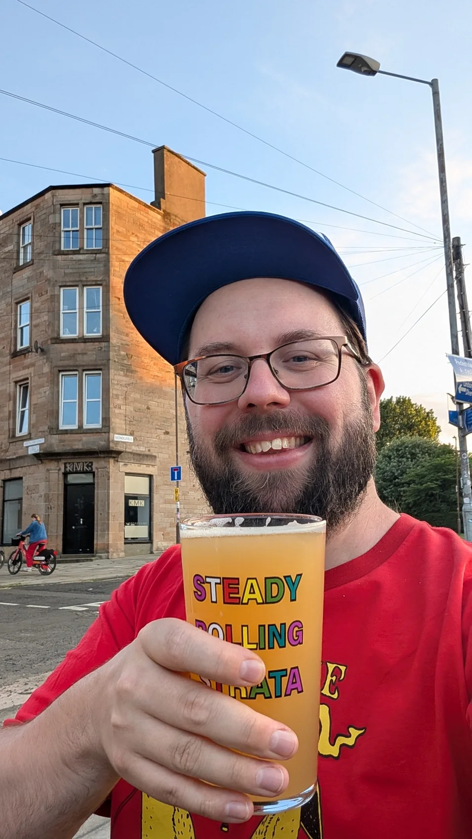 Sandro smiling and raising a glass of hazy beer outdoors